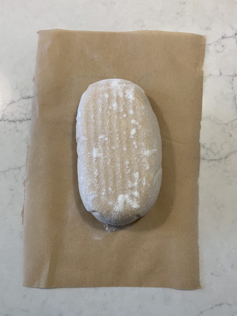 The oval loaf sitting on the parchment paper